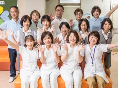 介護施設のスタッフ団体写真。白衣や介護服を着た職員が笑顔で集合。